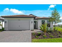 Beautiful one-story home with a two-car garage, neutral colors and appealing landscaping on a sunny day at 17093 Moonflower Dr, Venice, FL 34293