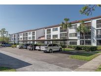 Condominium building with reserved parking spaces and mature landscaping around the building at 2595 Countryside Blvd # 8205, Clearwater, FL 33761