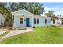 Charming light blue bungalow featuring a cozy front porch, neat landscaping, and well-maintained lawn at 3906 N Ola Ave, Tampa, FL 33603