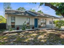 Charming single-story home featuring a blue door, inviting front entrance, and well-maintained landscaping at 7050 Jenner Ave, New Port Richey, FL 34655
