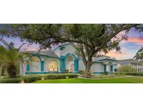 Stunning exterior of a home with blue trim, lush landscaping, and mature trees providing shade and curb appeal at 7314 Hunt Club Ln, Seminole, FL 33776