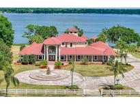 Stunning waterfront home with red tile roof, circular driveway, and lush landscaping at 11715 Taylor Rd, Thonotosassa, FL 33592