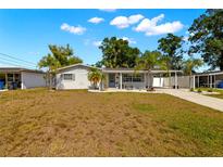 Charming single-story home features a well-maintained front yard, mature trees, and a covered carport at 14917 Philmore Rd, Tampa, FL 33613