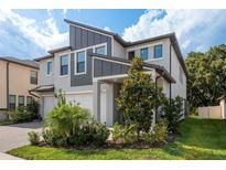 Charming two-story home featuring a well-manicured lawn and a beautifully landscaped front yard with mature trees at 21590 Violet Periwinkle Dr, Land O Lakes, FL 34637