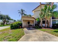 Two-story exterior with a covered carport, lush tropical landscaping, and a well-maintained lawn at 2600 Forest Run Ct, Clearwater, FL 33761