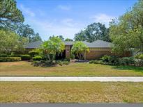 Charming single-story brick home with lush landscaping, vibrant green grass, and well-manicured palm trees at 3309 Westmoreland Dr, Tampa, FL 33618