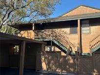 Condo exterior features a wood facade, stairs leading to the front door, and a carport with a covered parking spot at 404 Lennox W Rd # 404, Palm Harbor, FL 34683