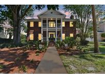 Elegant two-story brick home featuring a grand porch with classic columns and a well-manicured front yard at 4309 W Robin Ln, Tampa, FL 33609