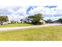 Expansive property featuring a charming white house, covered parking, and large green lawn at 812 Jameson Rd, Lithia, FL 33547