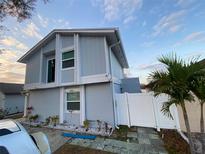 Two-story townhouse boasts a freshly painted exterior, a white fence, and a well-manicured lawn at 10414 Rosemount Dr, Tampa, FL 33624