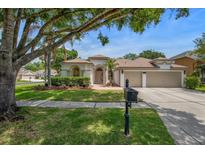 Charming single-story home with lush landscaping, a three-car garage, and a well-manicured lawn at 12806 Castlemaine Dr, Tampa, FL 33626
