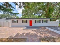 Charming single story home with red door, dark shutters and a brick driveway at 13110 Mitchell St, Tampa, FL 33612