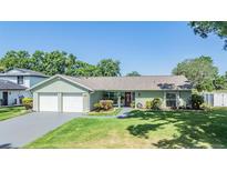 Charming single-story home featuring an attached two-car garage and well-maintained landscaping at 16214 W Course Dr, Tampa, FL 33624