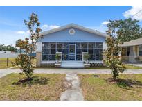 Charming single Gathering home featuring a screened-in front porch, blue siding, and mature trees at 2217 Stuart St, Tampa, FL 33605