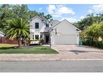 Charming two-story home with a well-manicured lawn, palm tree, and a basketball hoop over the garage at 3221 W Oakellar Ave, Tampa, FL 33611