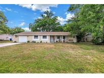 Charming single-story home with a covered porch and a swing, set in a lush, green front yard under a sunny sky at 3753 Hollow Oak Pl, Land O Lakes, FL 34639
