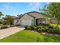 Charming single-story home with stone accents, a three-car garage, manicured lawn, and inviting front porch at 4220 Barletta Ct, Wesley Chapel, FL 33543