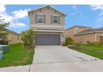 Two-story home with a two-car garage, neutral paint, minimalist landscaping, and shutters on the upper windows at 5068 Little Stream Ln, Wesley Chapel, FL 33545
