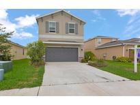 Two-story home featuring a neutral facade, gray shutters, a two-car garage, and a well-maintained front lawn at 5068 Little Stream Ln, Wesley Chapel, FL 33545
