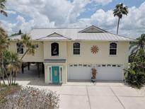Charming two-story home with a two car garage and decorative sunburst detail under a partly cloudy sky at 9914 Alavista Dr, Gibsonton, FL 33534