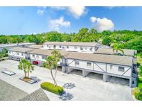 Two-story condo building featuring tropical landscaping, covered parking, and a light gray and white exterior at 1137 King Arthur Ct # 501, Dunedin, FL 34698