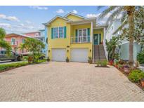 Bright yellow two-story home with a brick driveway, two-car garage, and lush tropical landscaping at 1326 Apollo Beach S Blvd, Apollo Beach, FL 33572