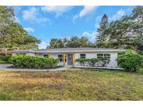 Charming single-story home featuring a well-maintained front lawn and inviting gray front door at 1905 Pine Tree Ln, Belleair Bluffs, FL 33770