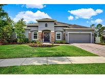 Charming single-story home featuring a manicured lawn, stone accents, and a welcoming front door with decorative wreath at 21028 Ski Way, Land O Lakes, FL 34638