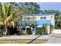 Charming two-story home with blue roof, mature landscaping, and a cozy beach vibe, offering a unique curb appeal at 2728 58Th S St, Gulfport, FL 33707