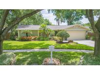 Charming single-story home with lush landscaping, mature trees, and a well-manicured lawn at 3714 Village Estates Pl, Tampa, FL 33618