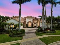 Gorgeous home at dusk featuring a red tile roof, mature landscaping and stately palm trees creating a warm and inviting ambiance at 5405 Tybee Island Dr, Apollo Beach, FL 33572