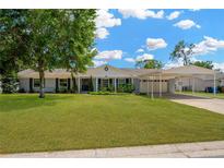 Charming single-story home with lush front lawn, mature tree, and attached carport at 607 Carolyn Dr, Brandon, FL 33510