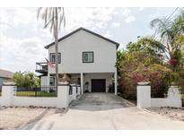 Modern two-story home featuring a gated driveway, lush landscaping, and an inviting facade at 7404 Bay Dr, Tampa, FL 33635