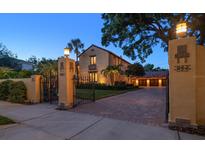 Elegant, gated home with a brick driveway, mature landscaping, and warm exterior lighting at dusk at 843 17Th N Ave, St Petersburg, FL 33704