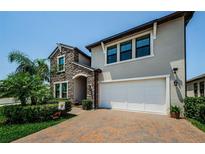 Charming two-story home with a paver driveway, a stone facade, and a two-car garage at 2653 Longleaf Pine Pt, New Port Richey, FL 34655