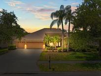 Inviting exterior view of a well-manicured home with palm trees and a spacious driveway at 5216 Kernwood Ct, Palm Harbor, FL 34685