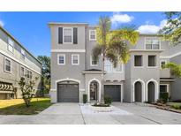 Three-story townhome featuring a gray facade, arched entryway, and a well-maintained driveway with landscaping at 616 Wheaton Trent Pl, Tampa, FL 33619