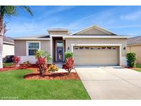 Charming one-story home featuring a well-manicured lawn, colorful foliage, and a neutral color scheme at 13414 Graham Yarden Dr, Riverview, FL 33579