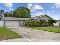 Charming single-story home with a well-manicured lawn and a long driveway leading to the garage at 1812 Teakwood Ln, Dunedin, FL 34698