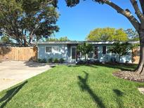 Charming light blue home featuring a well-manicured lawn and mature trees, providing excellent curb appeal at 1818 Douglas Ave, Dunedin, FL 34698