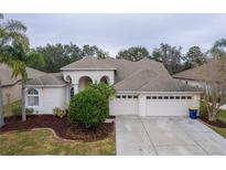 Charming home featuring a three-car garage, arched entrance, and well-maintained landscaping at 21215 Tyrell Way, Land O Lakes, FL 34638