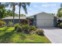 Charming home exterior with mature landscaping, palm trees, and a two-car garage at 2810 Doone Cir, Palm Harbor, FL 34684
