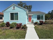 Charming light blue single-story home with a well-manicured lawn and a bright coral front door at 3501 7Th N Ave, St Petersburg, FL 33713