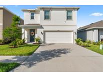 Charming two-story home featuring a well-manicured lawn, inviting curb appeal, and a two-car garage at 35780 Sunflower Hill Dr, Zephyrhills, FL 33541