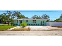 Charming single-story home with a light green exterior, complemented by a well-manicured lawn and landscaped garden at 5030 9Th S Ave, Gulfport, FL 33707