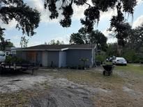 Modest single-story home, showing the front and side, with a wheelbarrow and parked car on a lot at 6206 Paul Buchman Hwy, Plant City, FL 33565