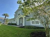 Stylish two-story home with a blue exterior, lush green lawn, and mature trees at 6304 Parkside Meadow Dr, Tampa, FL 33625