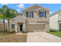 Two-story home featuring desert landscaping, a two car garage, and neutral stucco with dark shutters at 6708 Hazelnut Spice Dr, Ruskin, FL 33573
