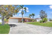 Charming single-story home features a well-maintained front yard, palm trees, and a spacious driveway leading to a two-car garage at 11535 64Th Ter, Seminole, FL 33772