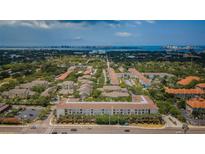 Wide aerial view of a multi-building residential complex with lush landscaping near coastal waters and distant cityscape at 1216 S Missouri Ave # 108, Clearwater, FL 33756